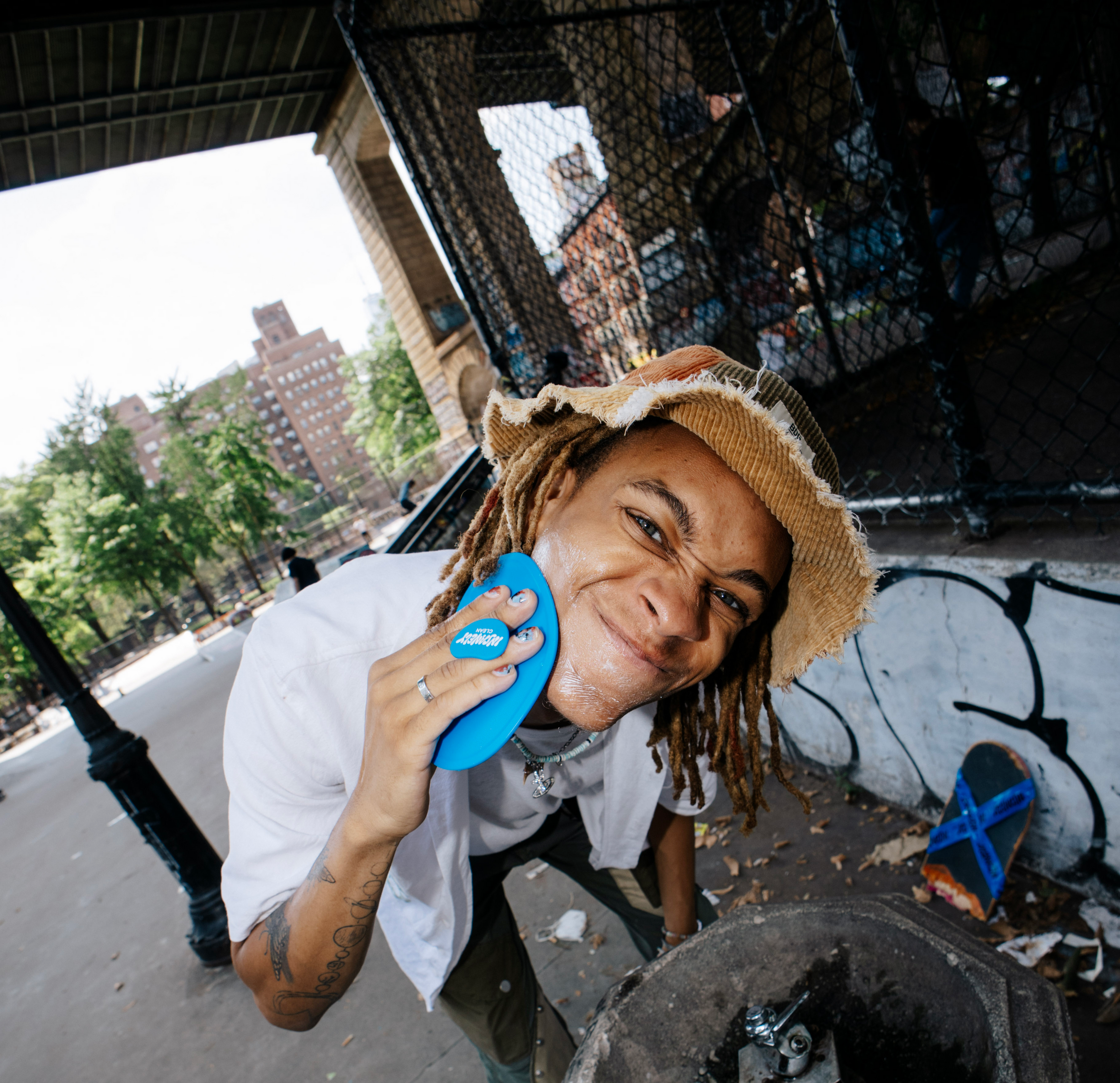 A cool, young man washing his face over a drinking foundation on a basketball court in the streets of New York City