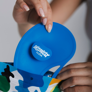 A hand removing the Insanely Clean blue silicone Scrubber from its packaging.