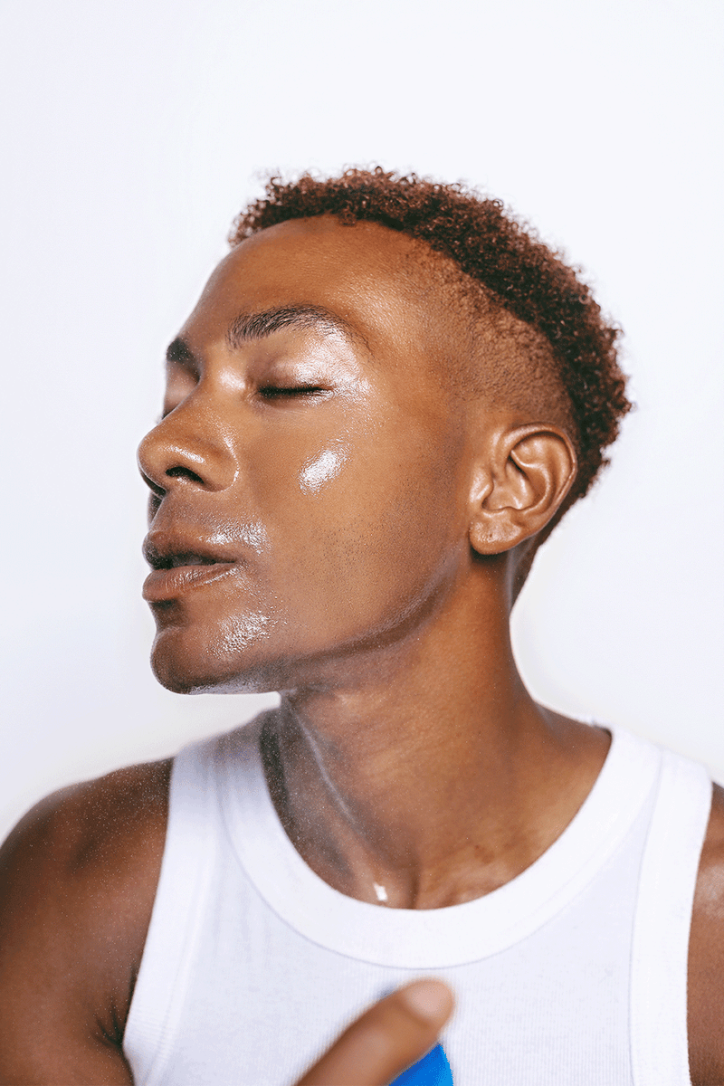 A man spritzing the best hydrating mist for men on his male face displaying a radiant skin.