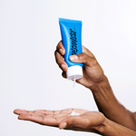 A hand squeezing a bottle of the best natural face wash for men for the male face.
